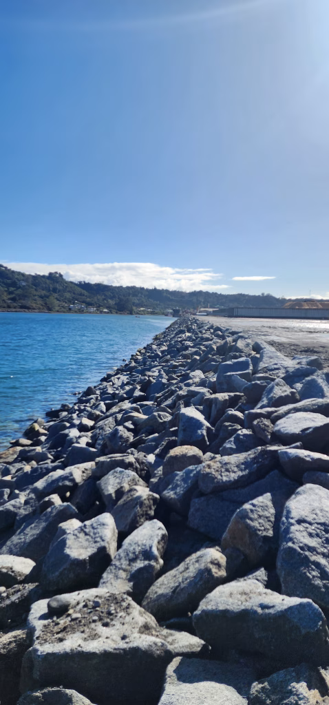 Vista del enrocado de protección construido en la costa durante la ampliación del Puerto Punta Caullahuapi, con el mar a un lado y el terreno del puerto al otro.