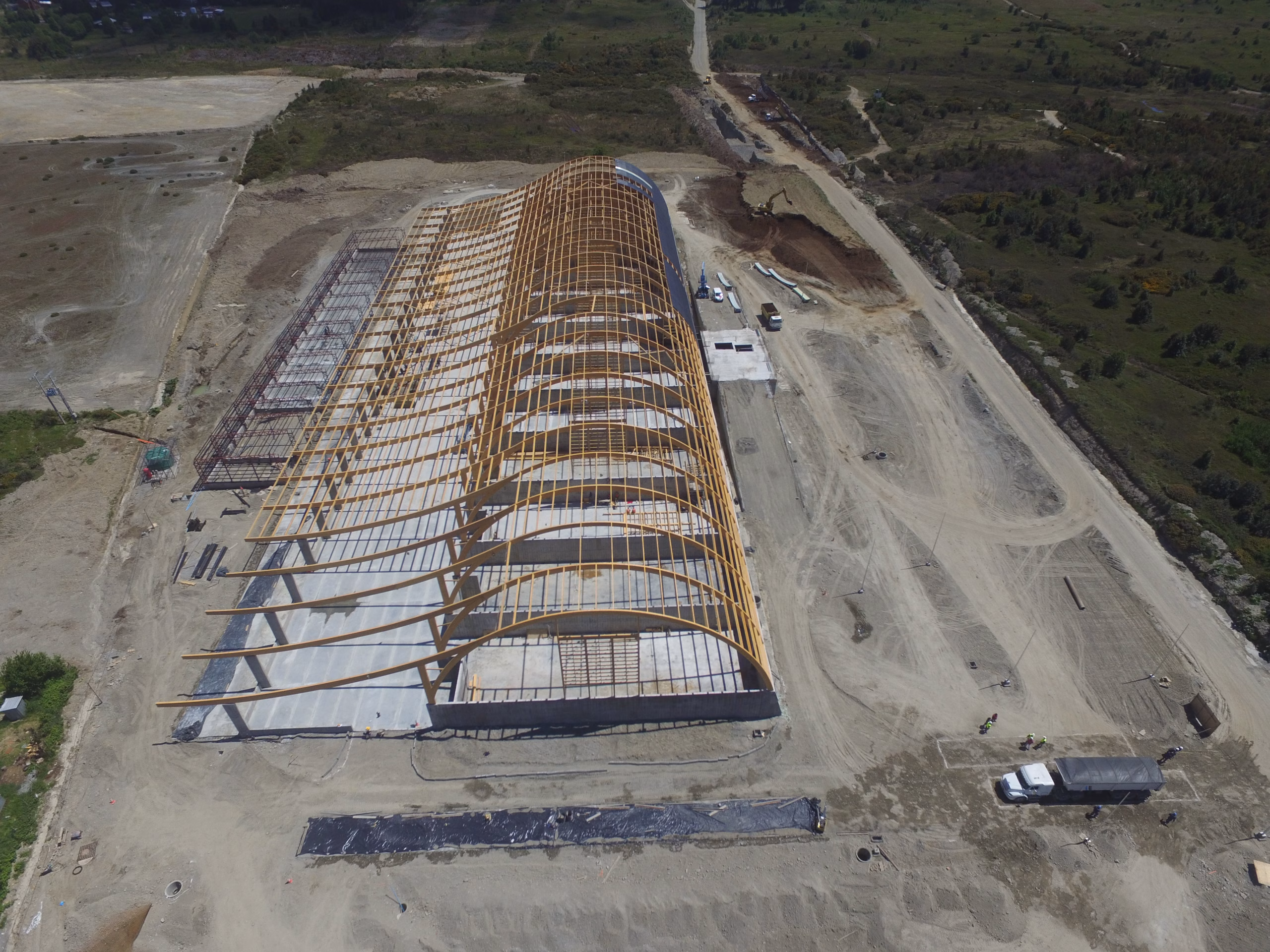 Fotografía aérea de la estructura de madera laminada de la bodega SQM en construcción, mostrando las vigas y arcos.