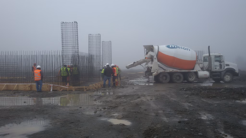 Obreros trabajando en la preparación de la cimentación con encofrados y hormigonera en la construcción de las Bodegas SQM.